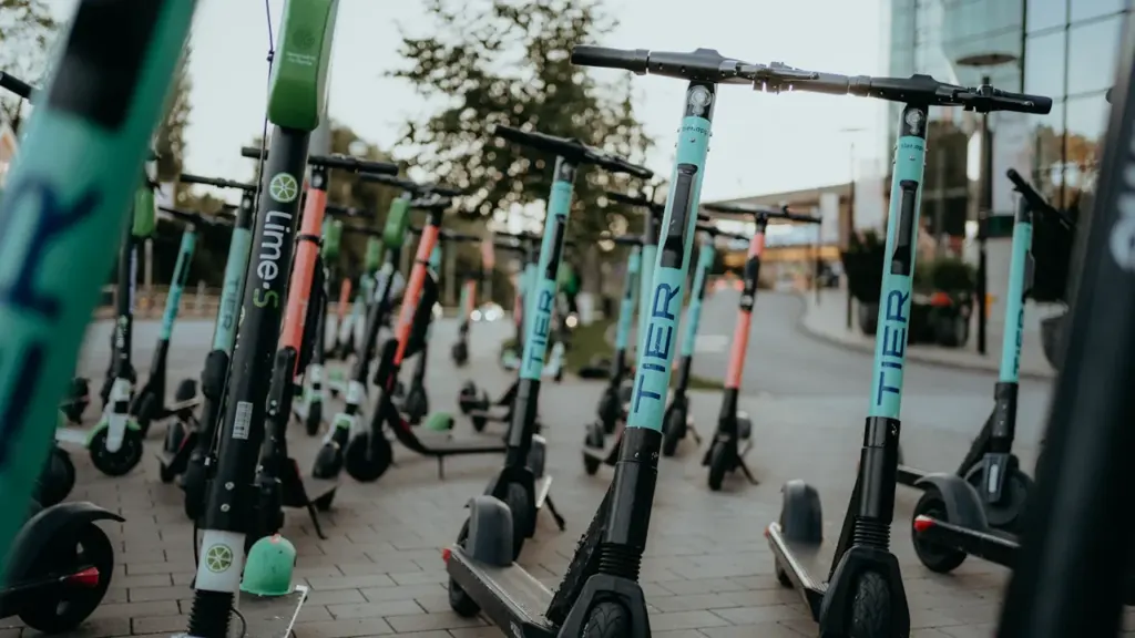 Plusieurs trottinettes électriques en libre-service stationnées sur un trottoir urbain.