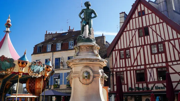 Statue et maisons à colombages dans une place historique ensoleillée de Dijon.
