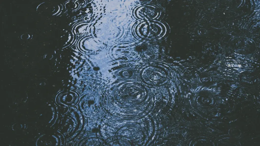 Pluie intense formant des cercles concentriques dans une flaque d'eau urbaine.