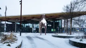 Une statue de chien devant une gare sous la neige en hiver.