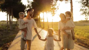 Une famille heureuse se promène sur un chemin arboré au coucher du soleil.