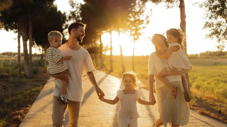 Une famille heureuse se promène sur un chemin arboré au coucher du soleil.