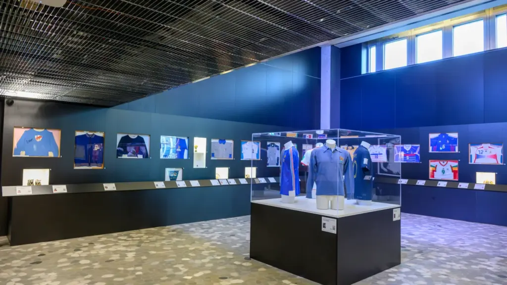 Exposition de maillots de football historiques sous vitrines dans un musée sportif moderne.