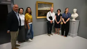 Un groupe de six personnes pose devant un tableau et un buste dans un musée.