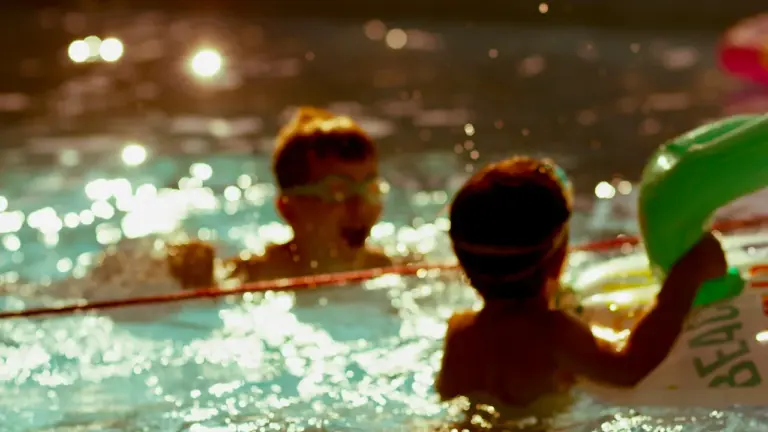 Deux enfants s'amusent dans une piscine lors d'une leçon de natation estivale.