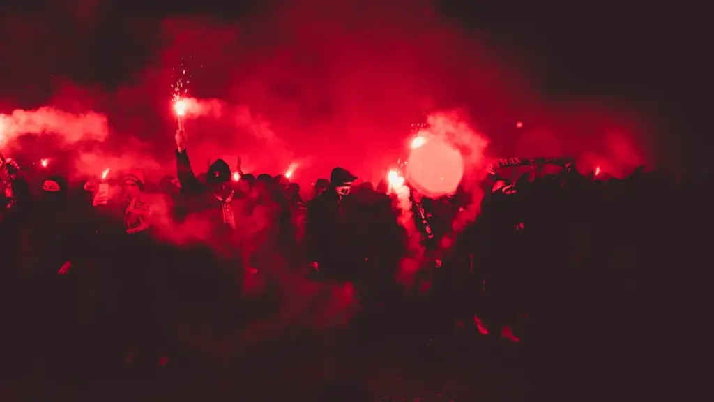 Ambiance festive avec fumigènes rouges lors d'une célébration sportive nocturne en France.