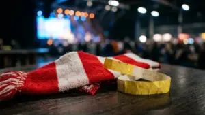 Une écharpe rouge et blanche rayée avec un bracelet d'accès jaune sur une table.