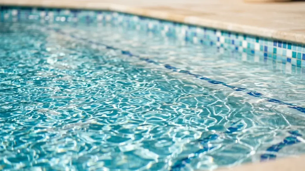 Vue en gros plan de l'eau claire et scintillante d'une piscine avec carreaux bleus.