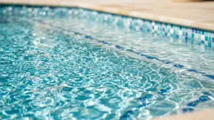 Vue en gros plan de l'eau claire et scintillante d'une piscine avec carreaux bleus.