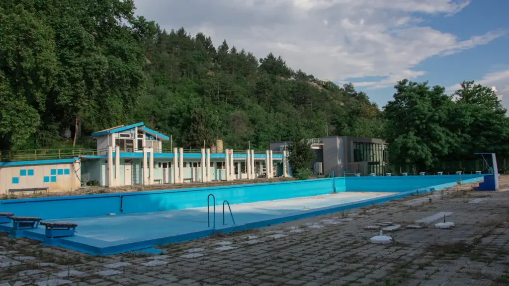 Piscine municipale en plein air vide avec un bâtiment en arrière-plan.
