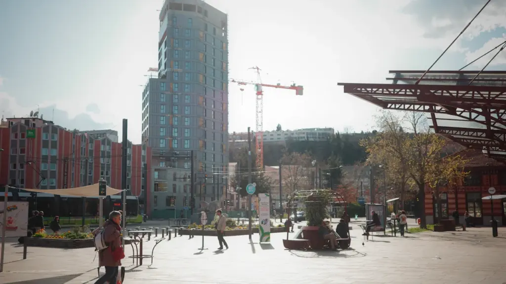 Vue urbaine de la gare de Châteaucreux à Saint-Étienne avec passants et architecture moderne.
