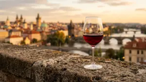 Un verre de vin rouge posé sur un muret en pierre surplombant Prague au coucher.