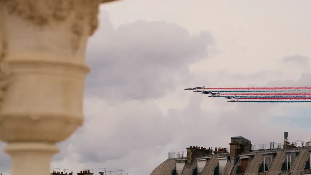 Patrouille de France survolant Paris avec des traînées de fumée tricolores lors du défilé.