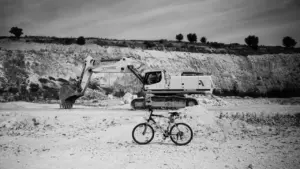 Un vélo garé devant une grande pelleteuse dans un chantier de construction.