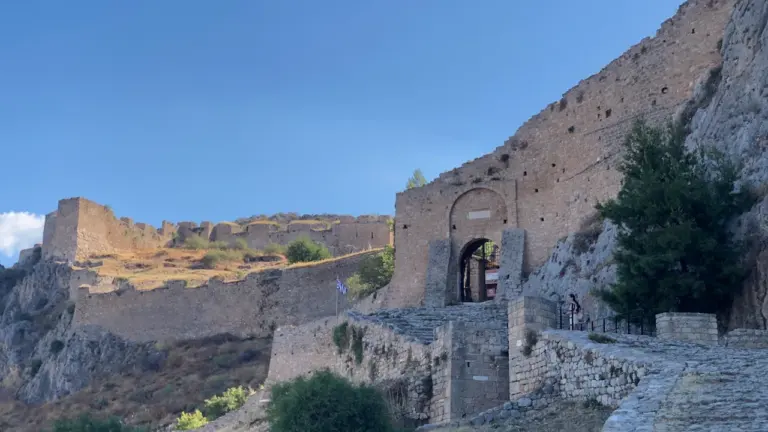 Vue des remparts anciens et d'une porte fortifiée en pierre sous le soleil.