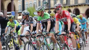 Un groupe de cyclistes professionnels en tenue de course roule sur une route urbaine.