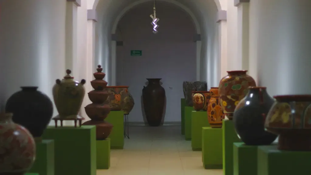 Plusieurs vases en faïence disposés sur des socles dans une galerie d'exposition.