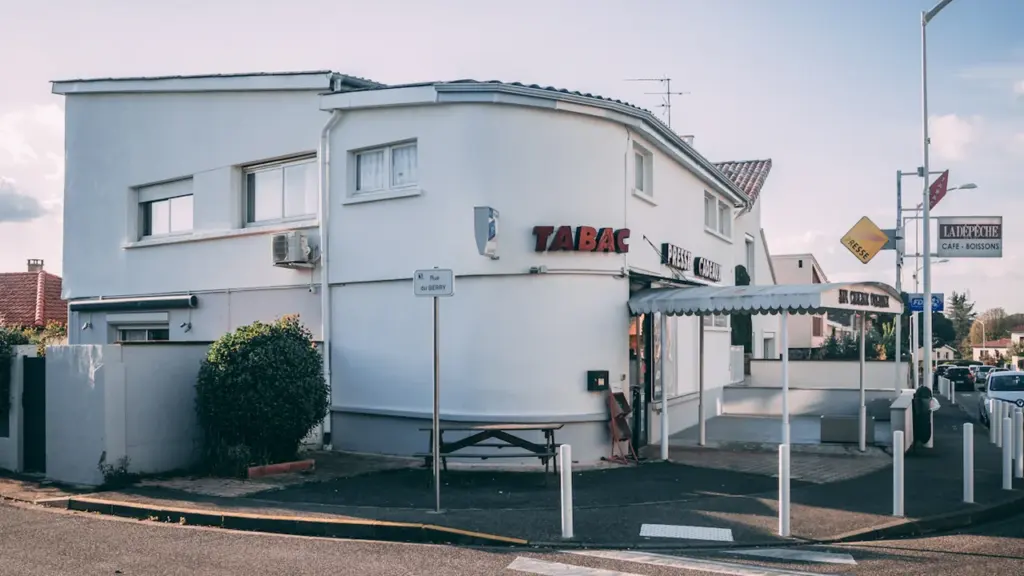 Façade d'un bâtiment blanc avec une enseigne Tabac dans une rue française typique.