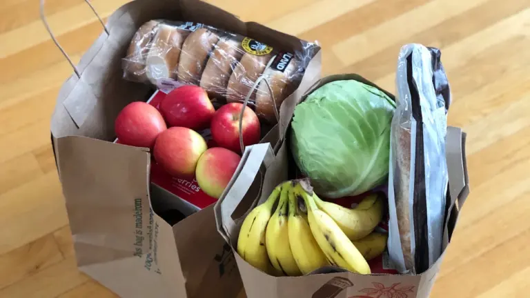 Sacs en papier kraft remplis de fruits frais, légumes et pain.