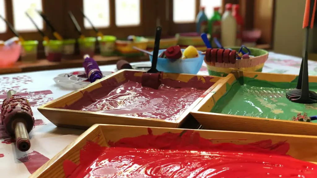 Plateaux de peinture colorée et pinceaux disposés pour des activités artistiques d'enfants.
