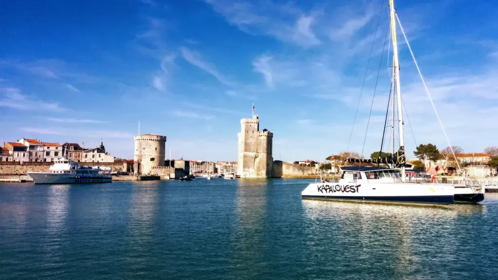 Vue ensoleillée du vieux port de La Rochelle et ses tours emblématiques.