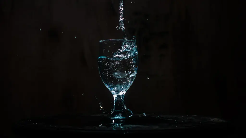 Un verre d'eau cristalline avec une éclaboussure artistique sur un fond sombre.