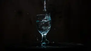 Un verre d'eau cristalline avec une éclaboussure artistique sur un fond sombre.