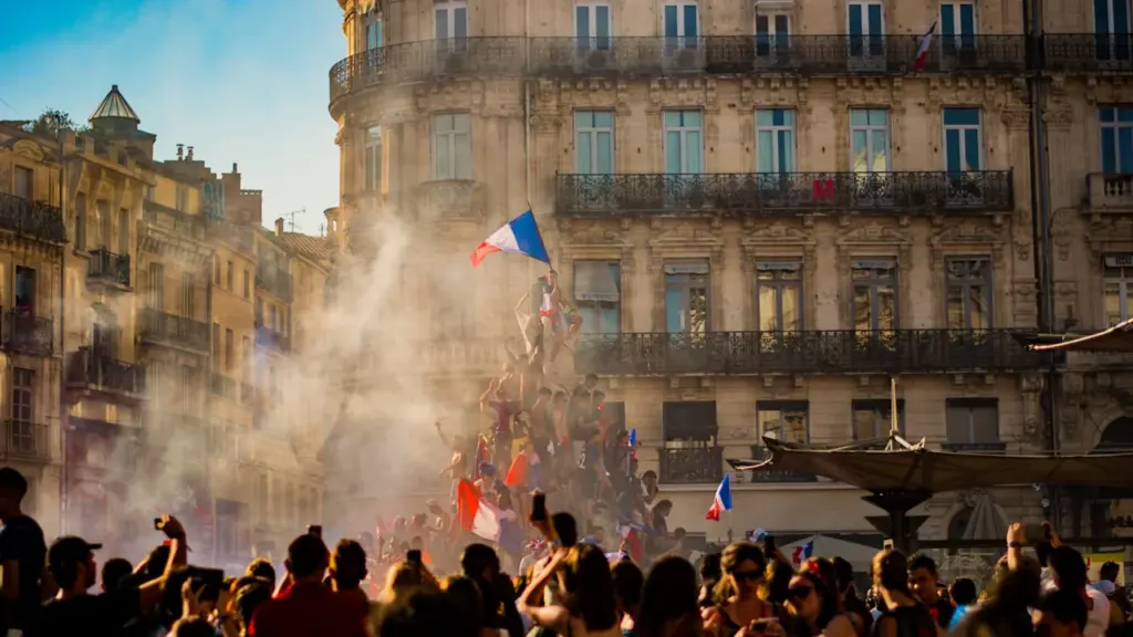 Foule célébrant lors d'un événement festif avec des drapeaux français en ville.