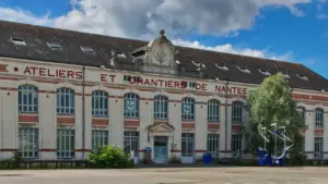 Façade du bâtiment des Ateliers et Chantiers de Nantes sous un ciel ensoleillé.