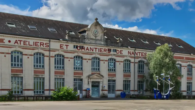 Façade du bâtiment des Ateliers et Chantiers de Nantes sous un ciel ensoleillé.