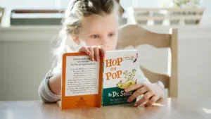 Une jeune fille concentrée lisant un livre dans un environnement calme et lumineux.
