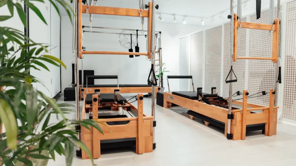 Studio de Pilates professionnel avec équipements en bois dans une salle lumineuse et épurée.