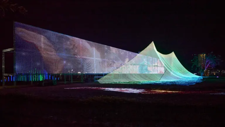 Grand écran géant illuminé projetant des images lors d'un événement nocturne en extérieur.