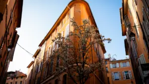 Immeuble aixois traditionnel avec une façade ocre dans une rue étroite et ensoleillée.