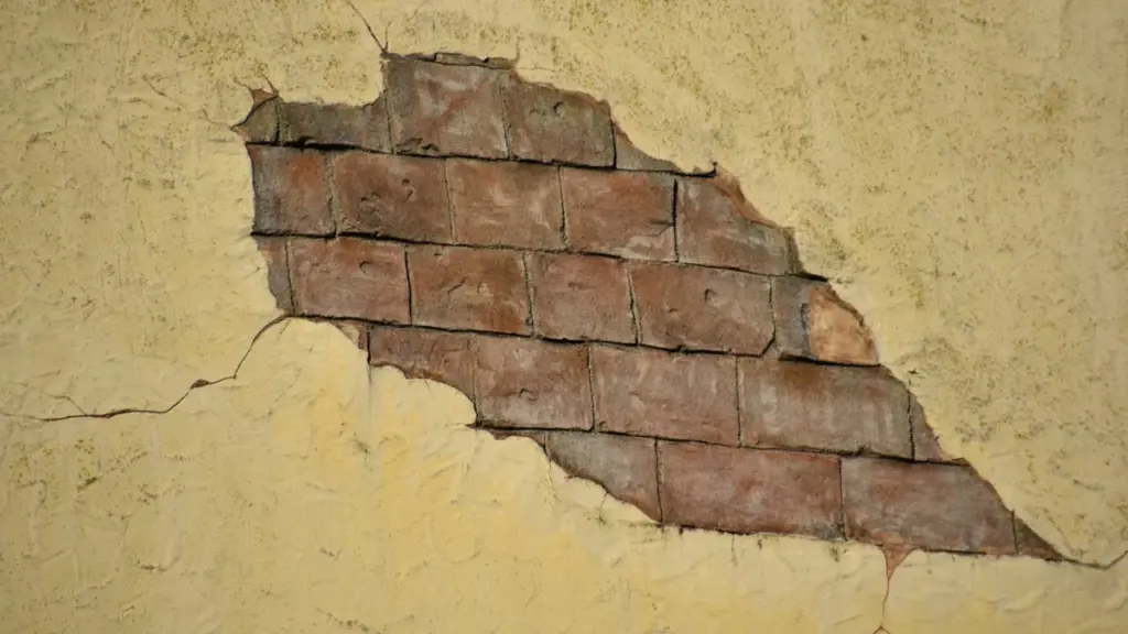 Mur extérieur en briques fissuré par la sécheresse sur un vieux bâtiment.