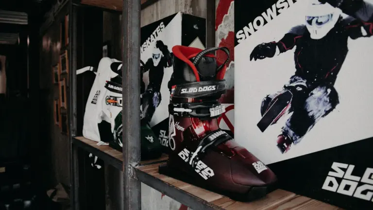 Chaussures de ski et équipement de sport hivernal sur une étagère en bois.