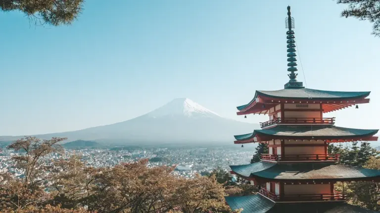 Pagode traditionnelle japonaise surplombant une ville avec le mont Fuji en arrière-plan.