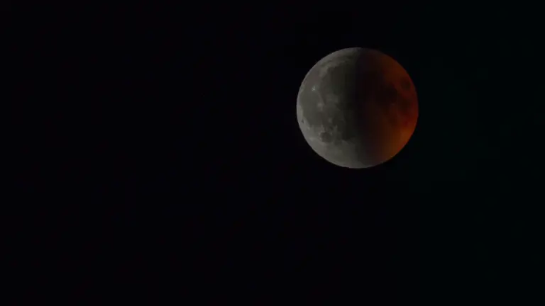 Une éclipse lunaire partielle montrant une partie de la lune sombre et orangée