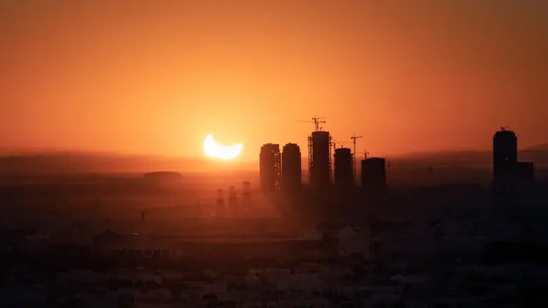 Une éclipse partielle du soleil au-dessus d'une ligne d'horizon urbaine au coucher du soleil.