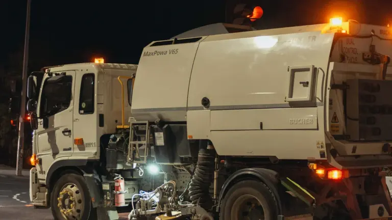 Camion de nettoyage urbain opérant dans les rues pendant la nuit avec gyrophares