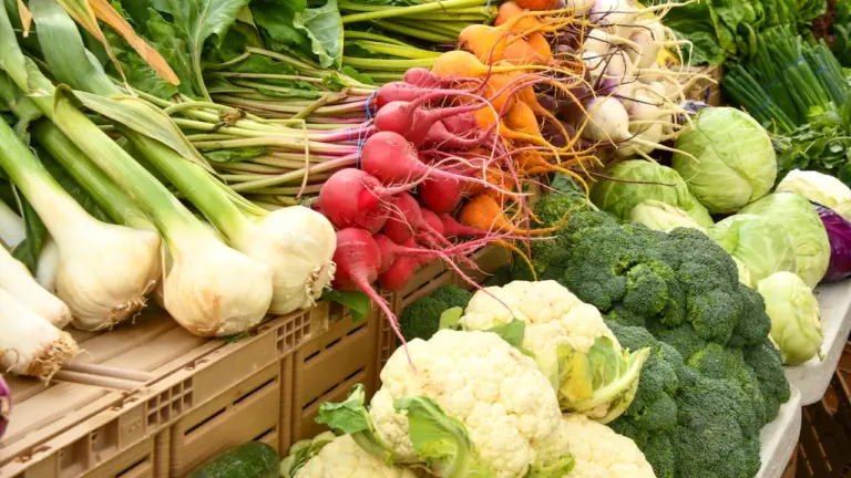 Un étal de marché local proposant des légumes frais, variés et colorés sur table.