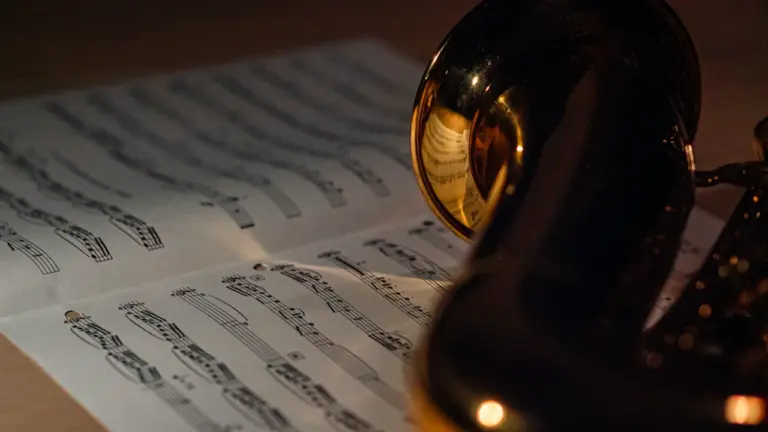 Un saxophone et des partitions posés sur une table en bois.