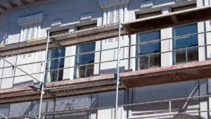 Échafaudage métallique installé devant la façade grise d'un immeuble historique en cours de rénovation.