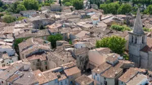 Vue aérienne d'un village provençal avec des toits en tuiles orangées et un clocher.