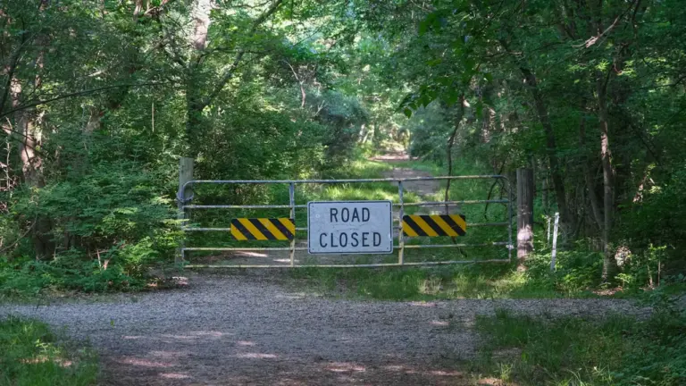 Panneau d'interdiction d'accès sur une grille métallique à l'entrée d'une forêt française.