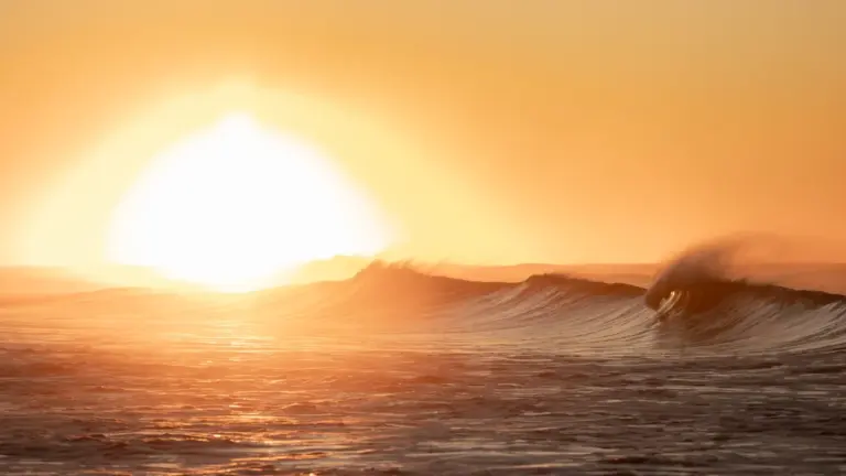 Coucher de soleil sur une vague océanique intense pour illustrer la chaleur estivale.