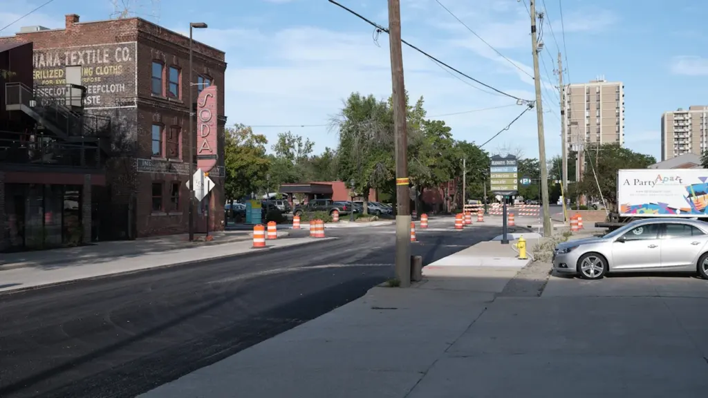 Vue d'une rue urbaine en travaux avec des cônes de signalisation orange.