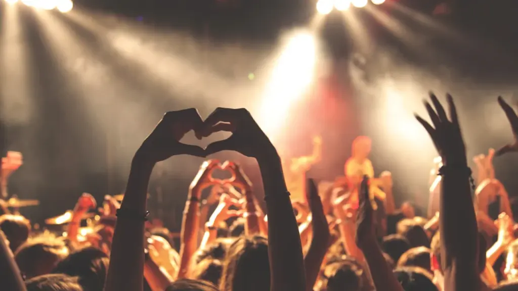 Foule enthousiaste lors d'un concert à Paris avec des mains formant un cœur.