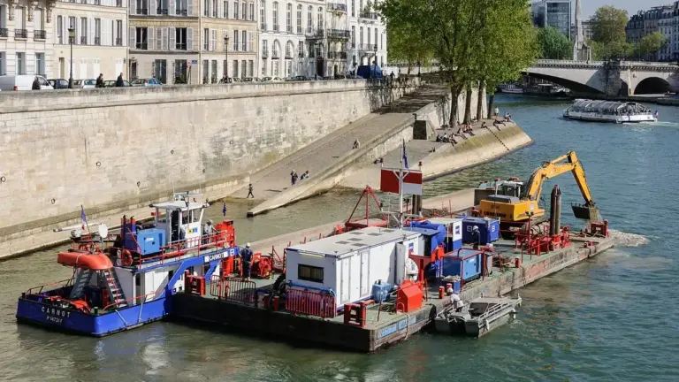 Une péniche équipée d'une pelleteuse jaune navigue sur la Seine dans le centre de Paris.
