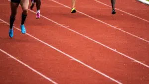 Plusieurs athlètes en pleine course sur une piste d'athlétisme rouge lors d'une compétition.